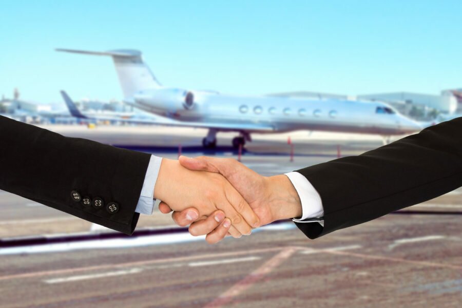 Two people shaking hands in front of a private chartered jet
